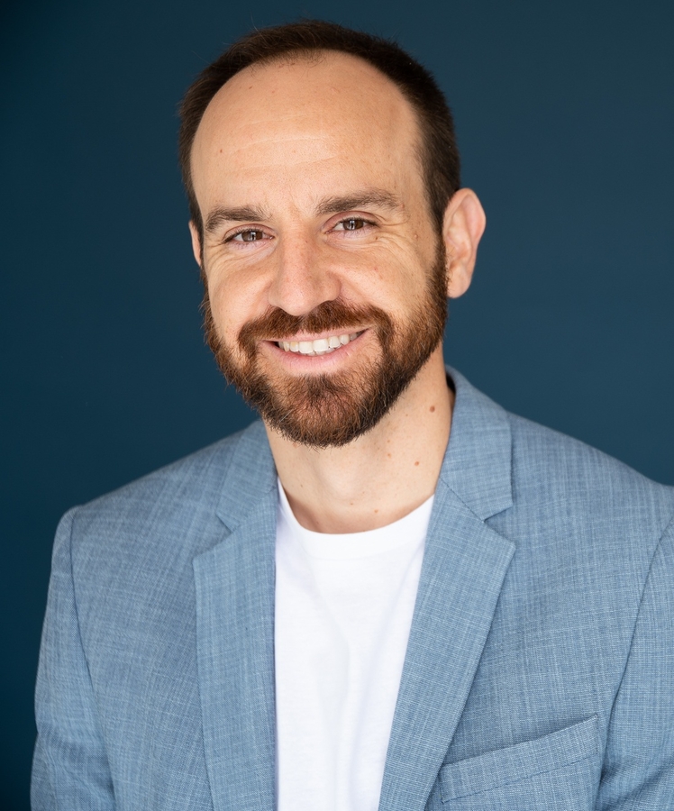 Paul Tacci smiling, wearing a suit